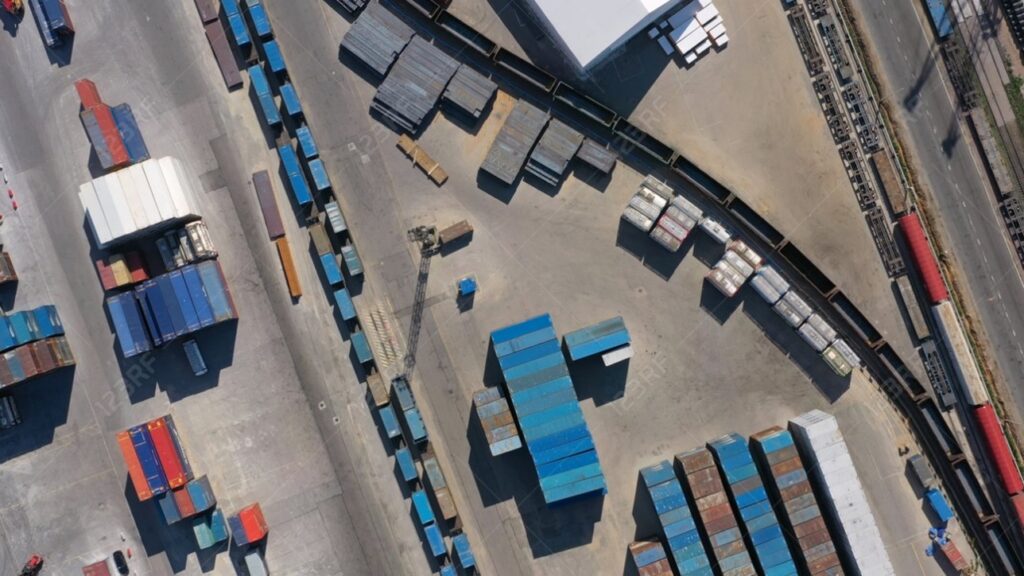 Luftaufnahme eines Containerterminals mit Güterzügen und Frachtcontainern.